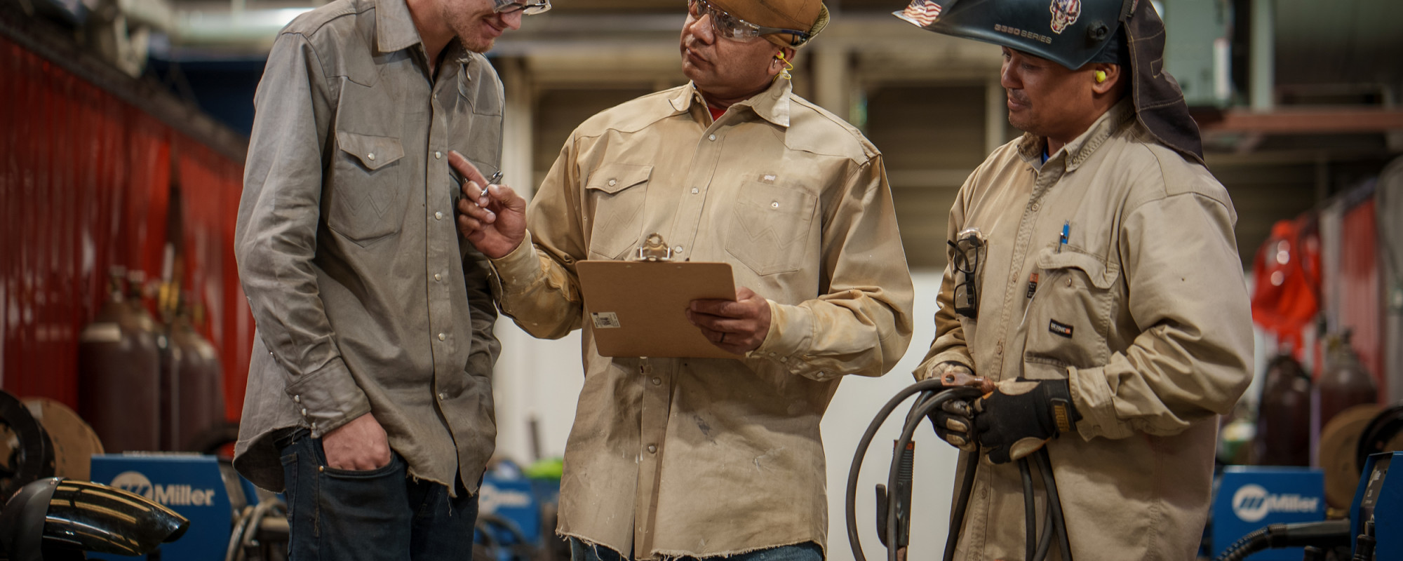 three welders discussing over a clipboard