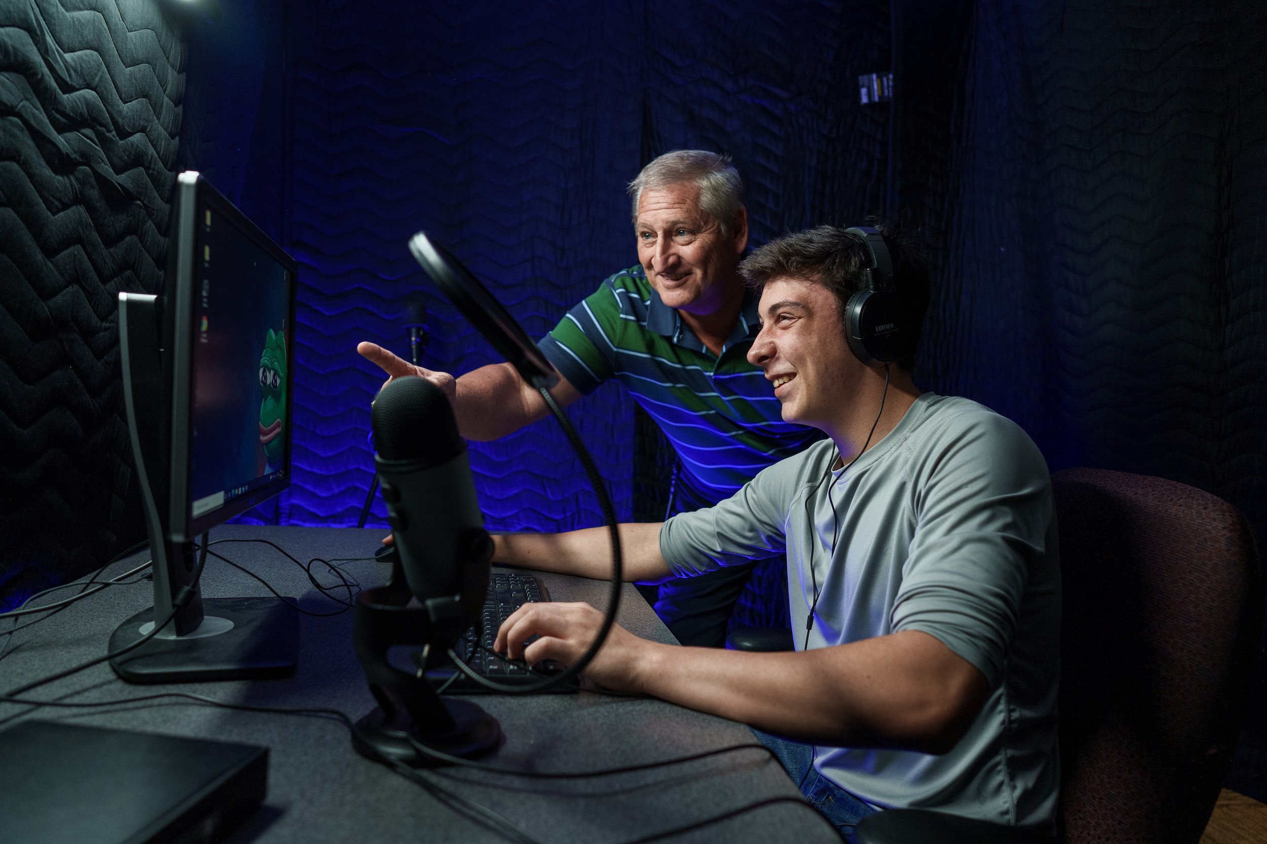a student and teacher in a soundbooth working at a computer